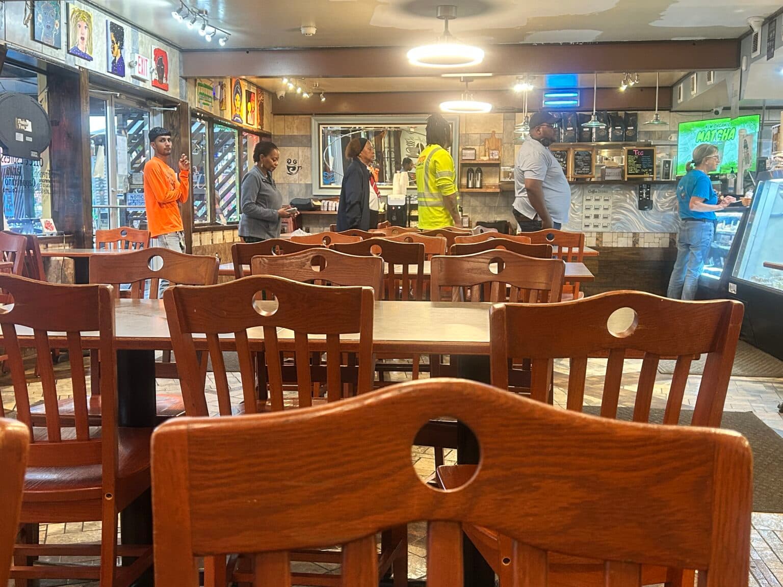 A view of empty tables with people in line at a café.