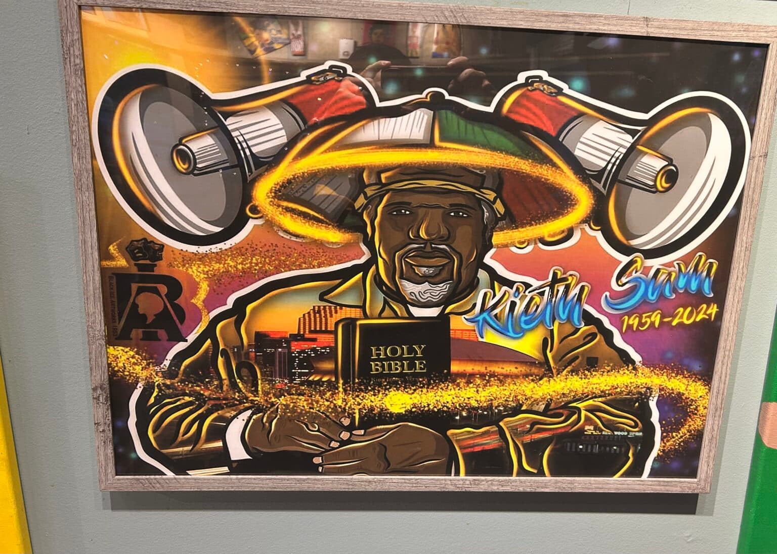 A vibrant tribute portrait of Kietu Sam, holding a Bible, framed by large speakers and colorful elements.