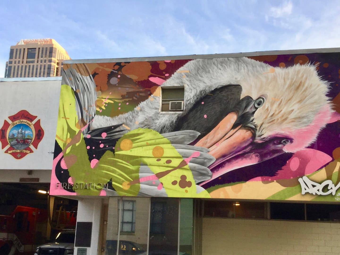 A vibrant mural featuring a colorful bird surrounded by abstract shapes on the side of a fire station.