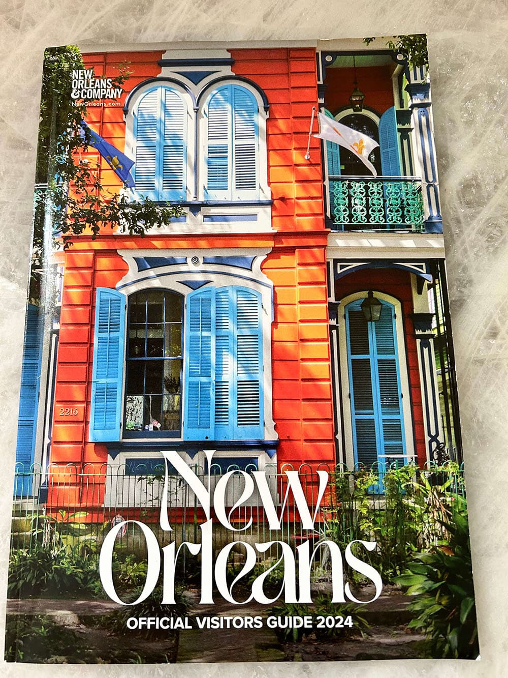 Cover of the 2024 New Orleans Official Visitors Guide featuring a brightly colored building with blue shutters.