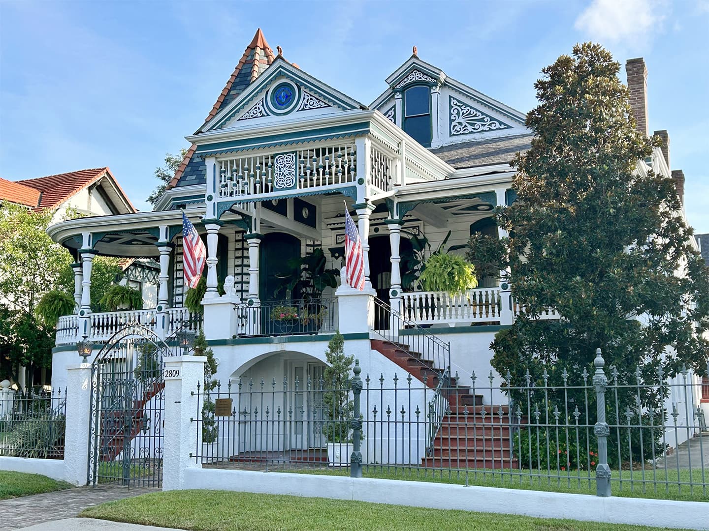 Historic Victorian-style house with intricate detailing and American flags.