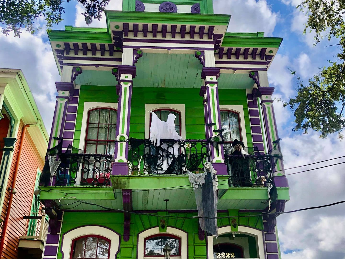 A brightly painted green and purple house decorated with ghostly figures for Halloween.