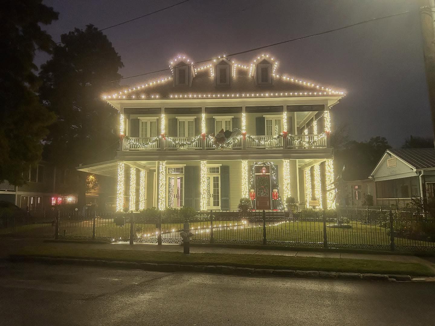 A beautifully lit two-story house adorned with decorative lights and wreaths during the evening.