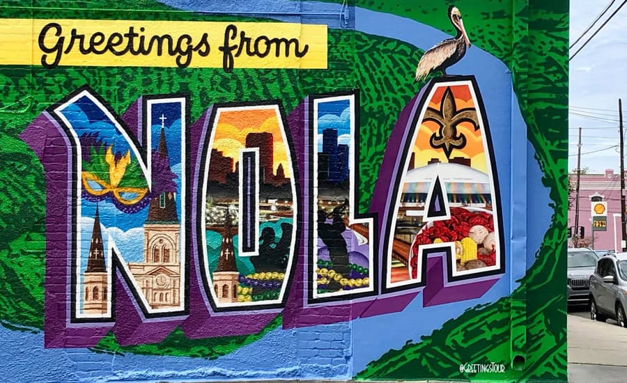 A colorful mural reading "Greetings from NOLA," featuring iconic local imagery and a pelican.