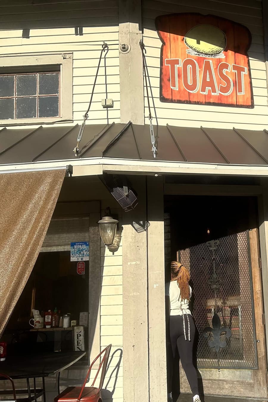 A woman approaches the entrance of a restaurant named "TOAST."