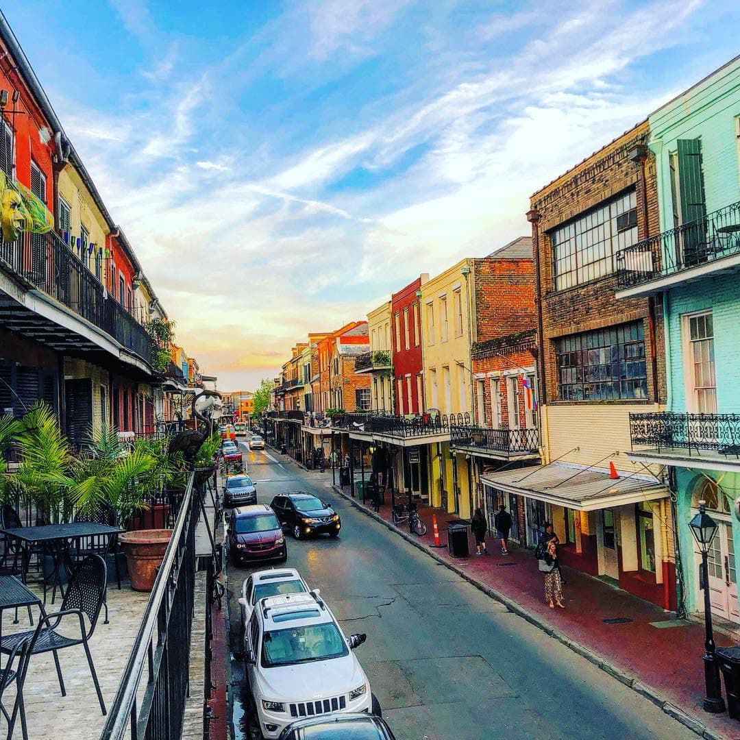 A colorful street lined with historic buildings and parked cars under a pastel sky.