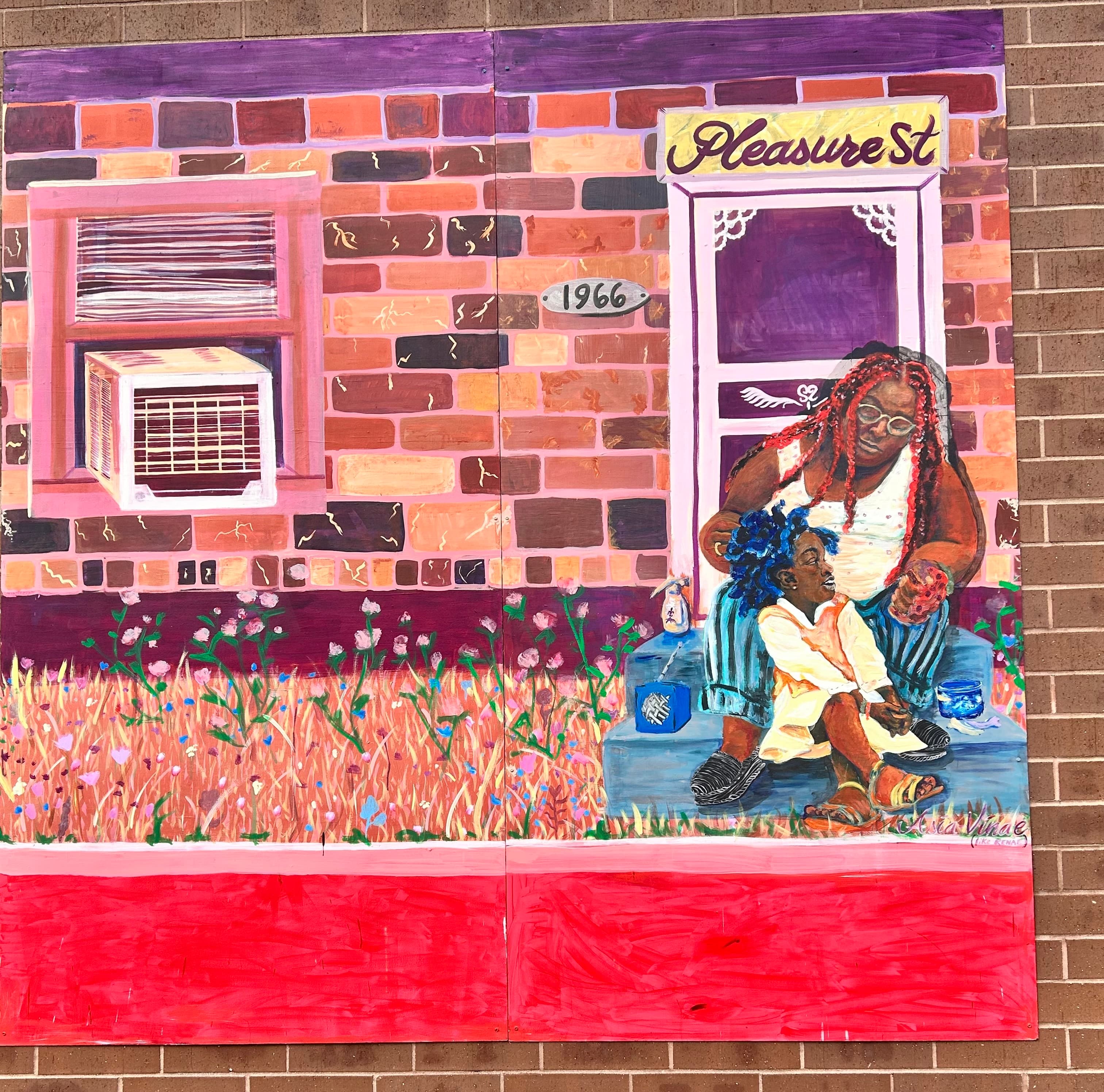 A colorful mural depicts a woman with braided hair sitting on steps with a child, surrounded by flowers and a brick wall labeled "Pleasure St." and "1966."