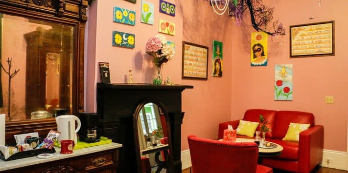 Cozy sitting area with red chairs, a decorative fireplace, and colorful wall art.