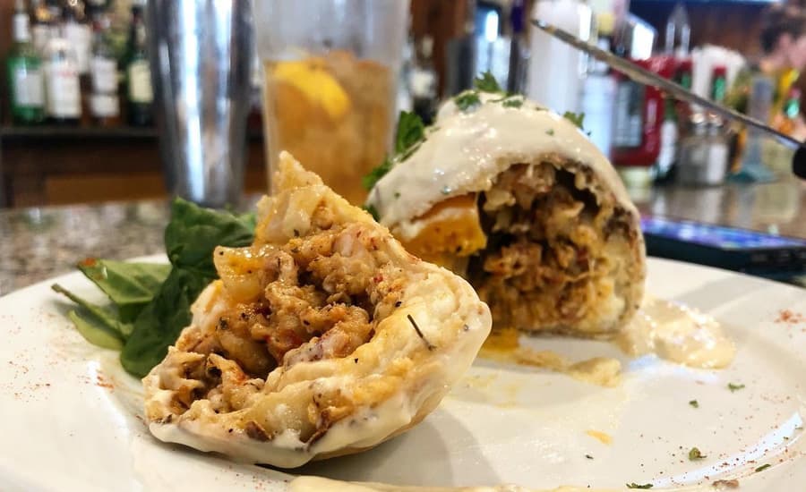 A plate with a partially cut burrito filled with savory ingredients, accompanied by fresh greens.