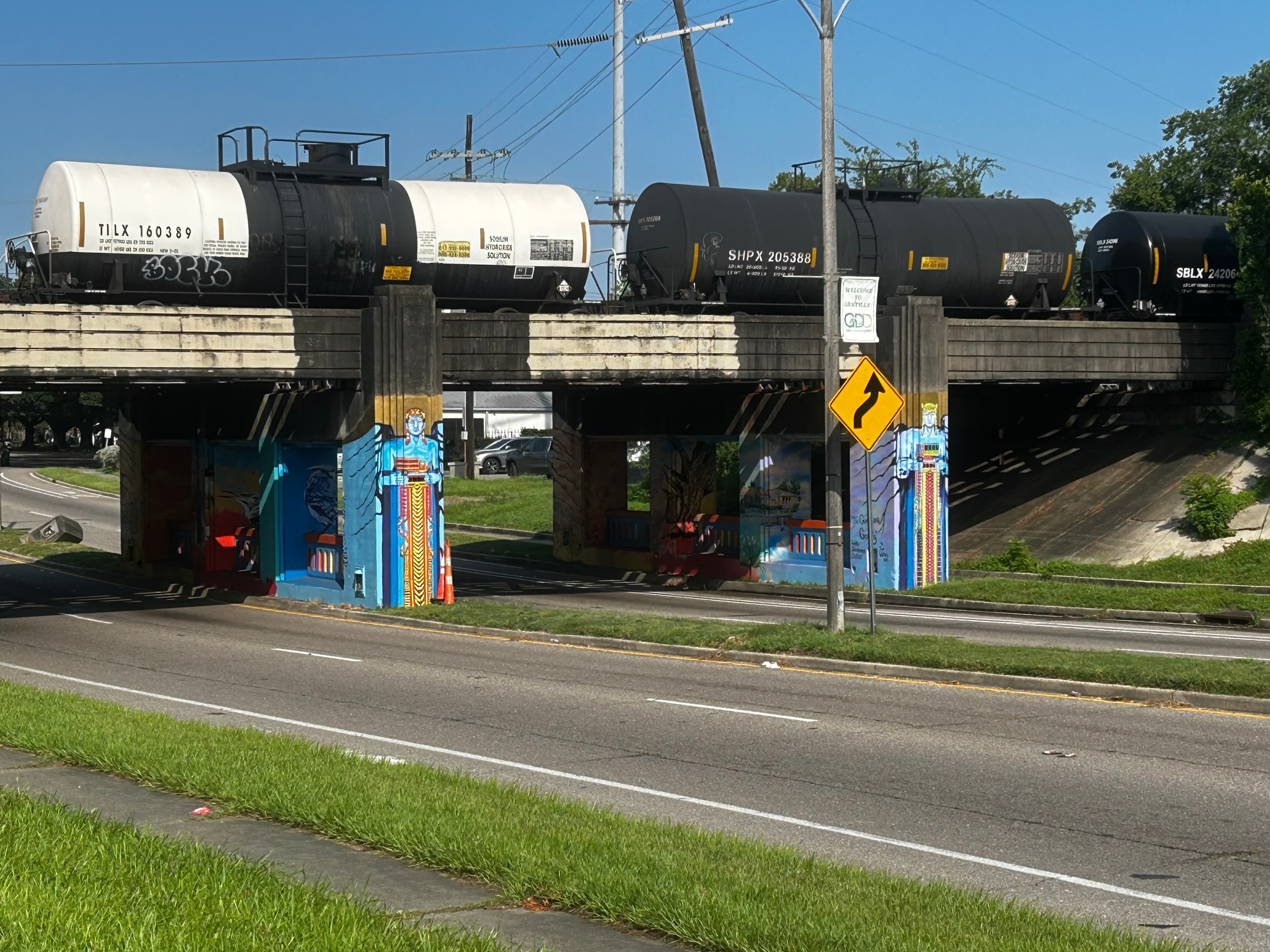 A train passes over a colorful underpass on a sunny day.