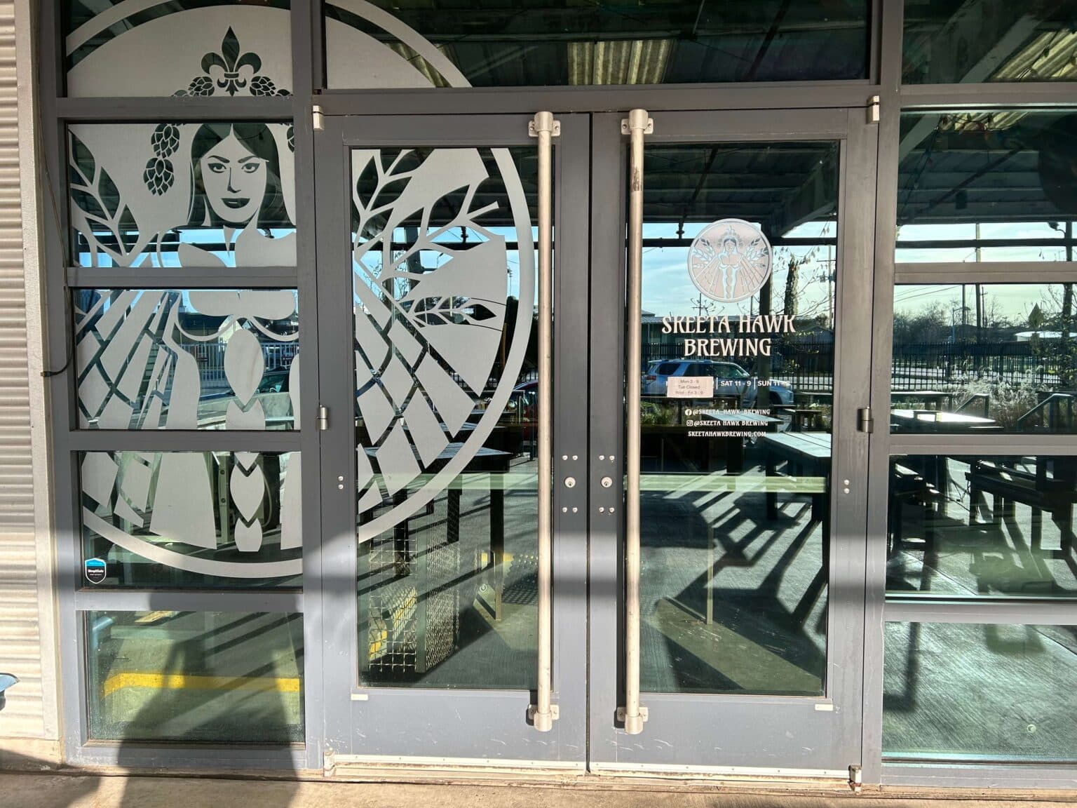 Double glass doors with a decorative illustration of a woman and the sign "Skelta Hawk Brewing."
