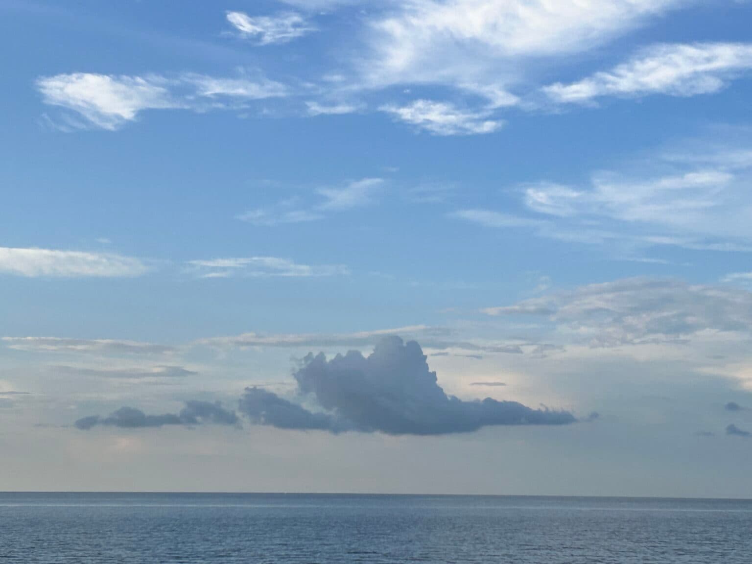 Beautiful calm sea and bright blue sky with fluffy white clouds Beautiful calm sea and bright blue sky with fluffy white clouds