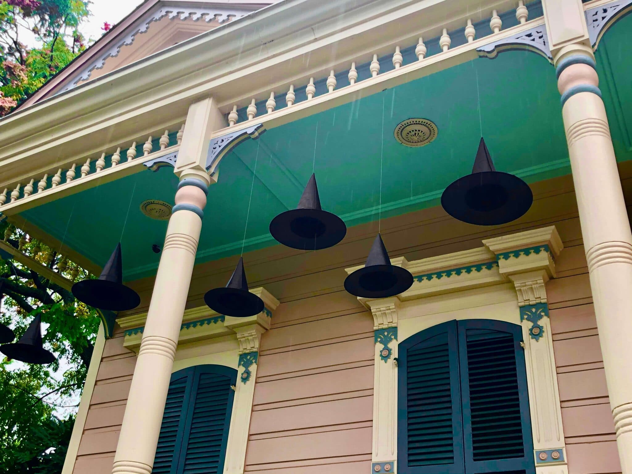A colonial style house with witch hats hanging on the front porch A colonial style house with witch hats hanging on the front porch